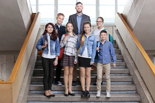 Счастливые ученики и учитель стоя на школьной лестнице — стоковое фото