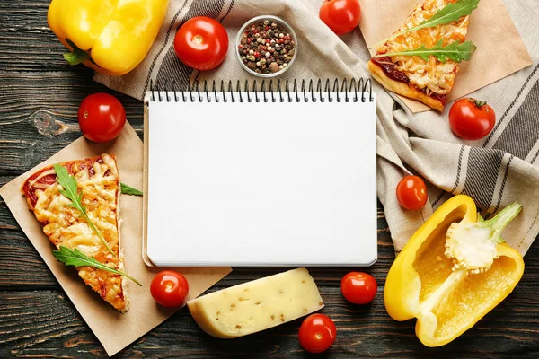 Натюрморт з інгредієнтами для піци та ноутбука рецептів на дерев'яному столі, вид зверху — стокове фото