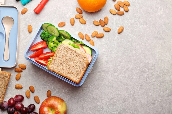 Lunch box with delicious food, fruits and almond on light textured background — Stock Photo, Image