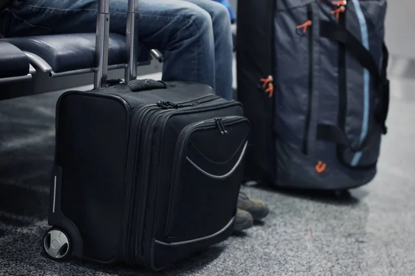 Bolsas de viaje cerca de las piernas del hombre — Foto de Stock