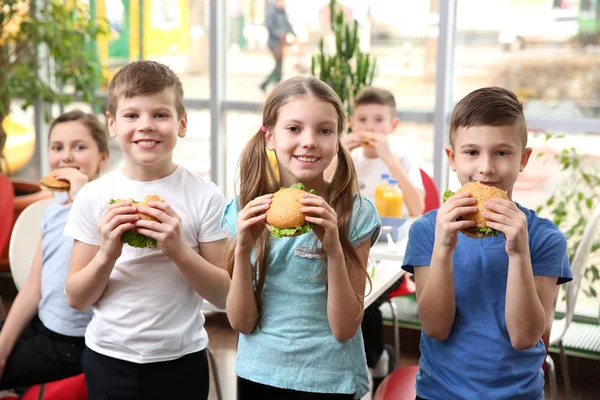 Barn Äter Hamburgare Skolmatsalen — Stockfoto