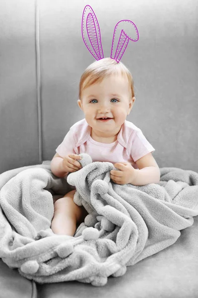 Το χαριτωμένο μικρό κορίτσι με συμένος bunny αυτιά που κάθεται στον καναπέ στο σπίτι — Φωτογραφία Αρχείου