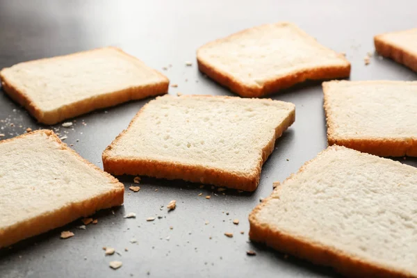 Slices and crumbs of wheaten bread on grey background — Stock Photo, Image