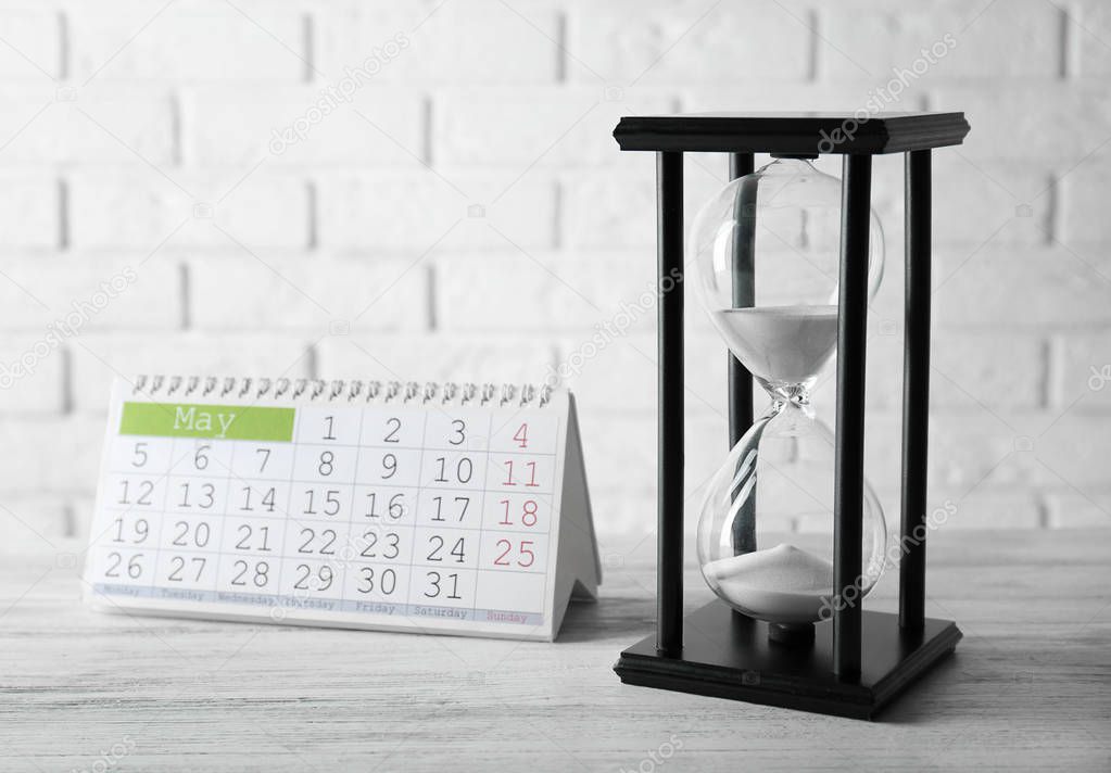 Hourglass with white sand and calendar  