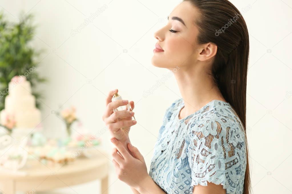 Beautiful young woman with bottle of perfume 