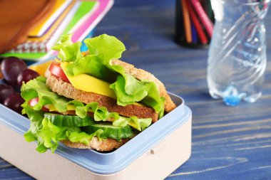 Lezzetli gıda ve Kırtasiye mavi ahşap arka plan üzerinde öğle yemeği kutusu