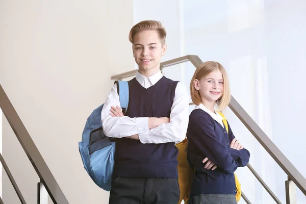 Okul üniformalı tatlı kız ve erkek merdivenlerde dikiliyor. — Stok fotoğraf