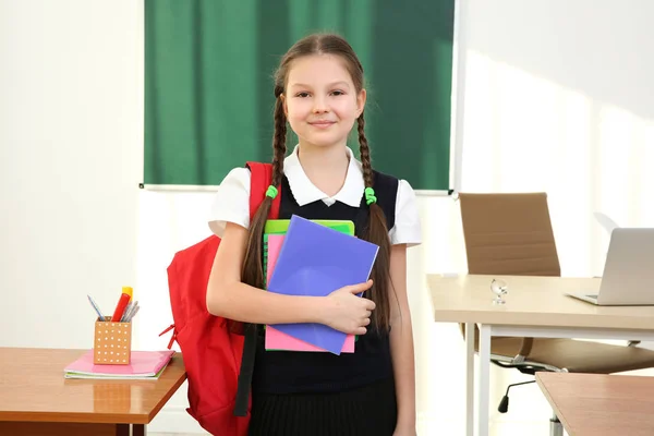 Retrato de una hermosa colegiala de pie en el aula — Foto de Stock