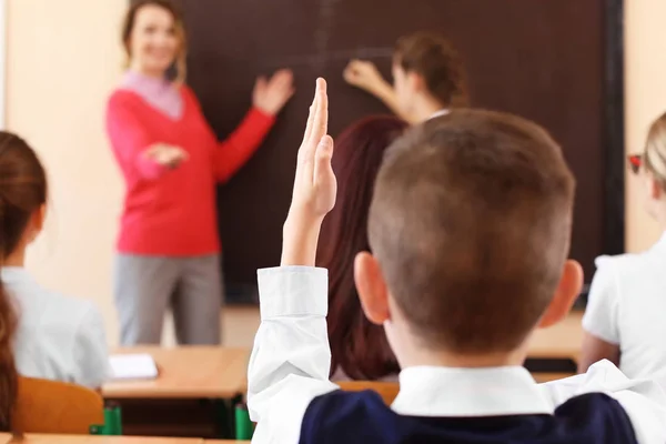 Alumno escuchando al maestro y levantando las manos para responder en el aula —  Fotos de Stock