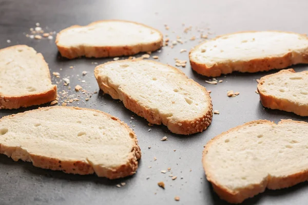 Fette e briciole di pane di grano con semi di sesamo su fondo grigio — Foto Stock