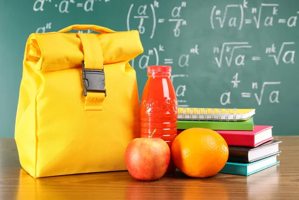 Lunchzak op houten tafelblad tegen schoolbord achtergrond — Stockfoto