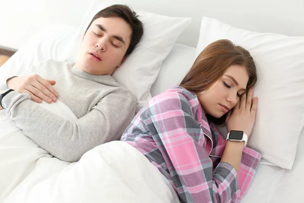 对年轻情侣在家里的床上休息的睡眠跟踪器 — 图库照片