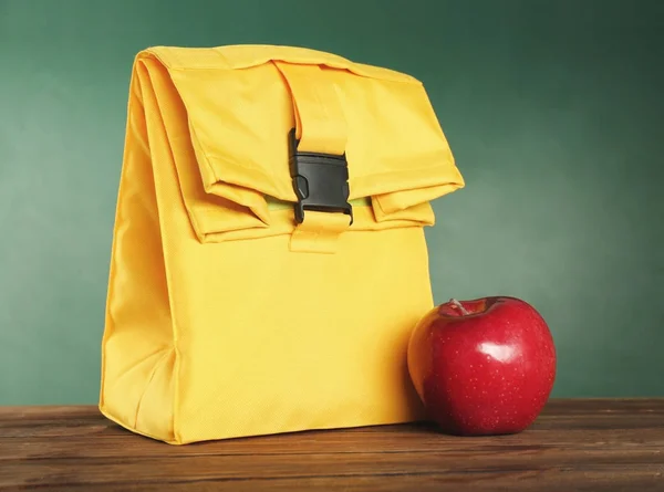 Yellow lunch bag and appetizing red apple