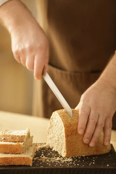 Руки человека режут хлеб — стоковое фото