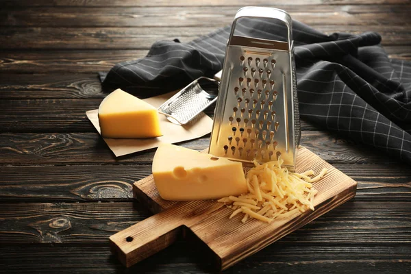 Grater and cheese on wooden board — Stock Photo, Image