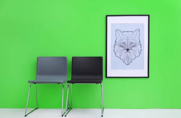 Современные стулья возле зеленой стены с абстрактной росписью — стоковое фото