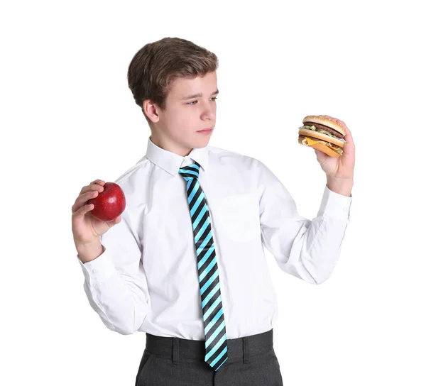 Симпатичный школьник с яблоком и гамбургером на белом фоне — стоковое фото