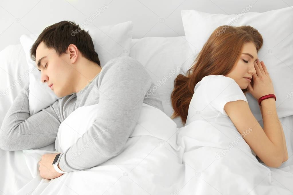 Young couple with sleep trackers resting in bed at home