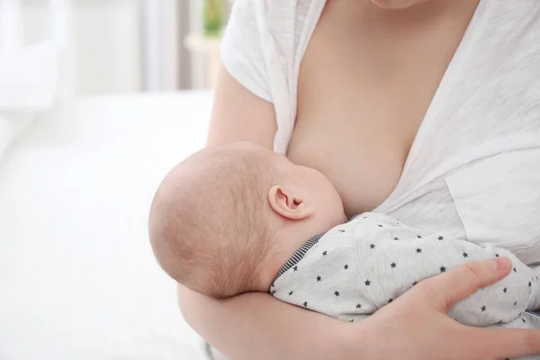 Молода жінка грудного вигодовування своєї маленької дитини вдома — стокове фото