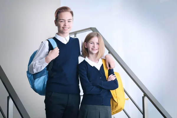 Bonito menino e menina no escola uniforme de pé no escadas — Fotografia de Stock