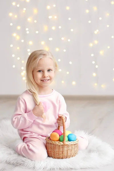 Roztomilá legrační dívka s košíkem plné velikonočních vajíček sedí na podlaze doma — Stock fotografie