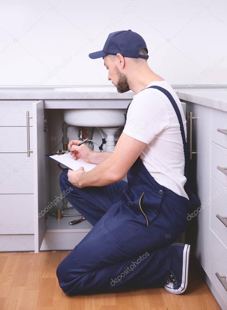 Plumber with clipboard near sink  