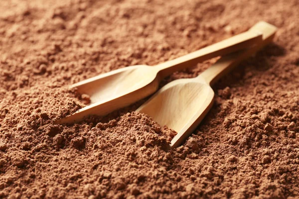 Wooden scoops on cocoa powder background — Stock Photo, Image