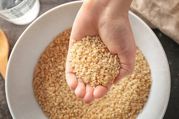 Woman holding heap of brown rice — Stock Photo, Image