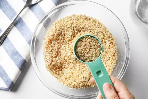 Measure scoop full of brown rice