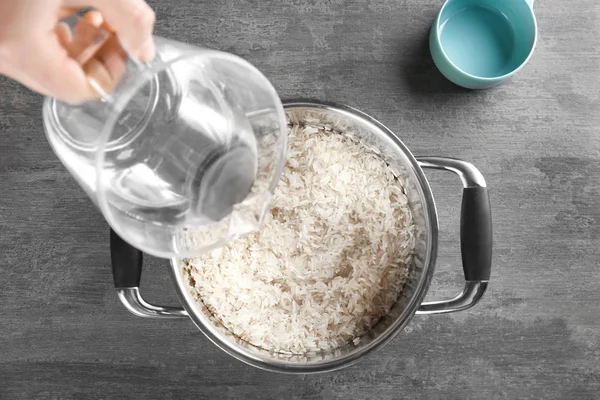 Verter agua en una cacerola con arroz —  Fotos de Stock