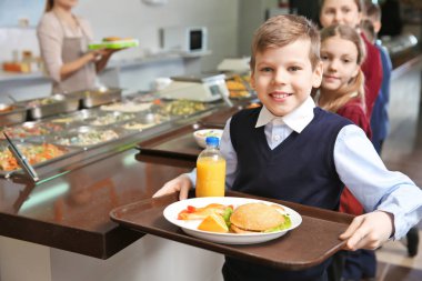 Sevimli kız lezzetli yemek tepsisiyle okul kafeteryasında holding
