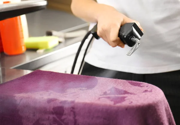Laundry worker removing stains using special equipment — Stock Photo, Image