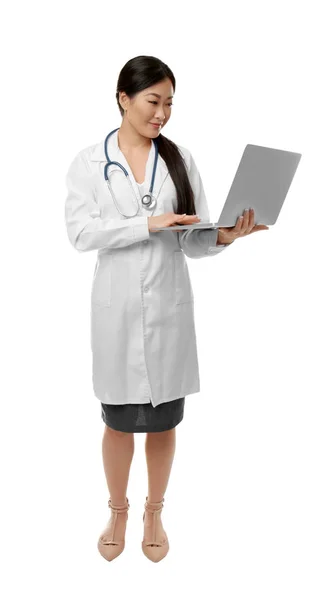 Médico bonito trabalhando com laptop de pé no fundo branco — Fotografia de Stock