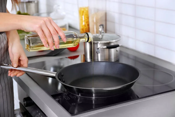 Closeup of woman pouring oil on frying pan — Stock Photo, Image