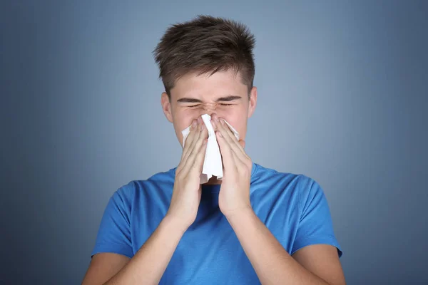 Young man blowing nose in tissue — Stock Photo, Image