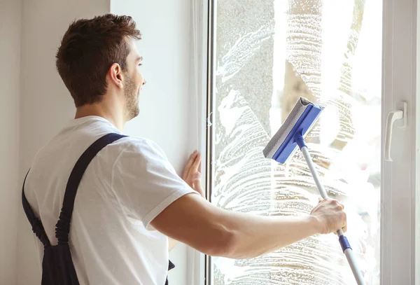 Hombre joven ventana de limpieza —  Fotos de Stock