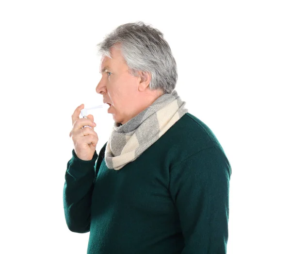 Zieke senior man met behulp van keel spray op witte achtergrond — Stockfoto