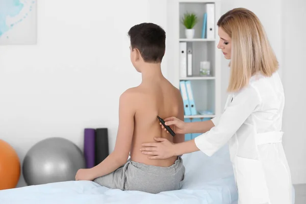 Concept de posture incorrect. Physiothérapeute examinant et corrigeant le dos du garçon — Photo