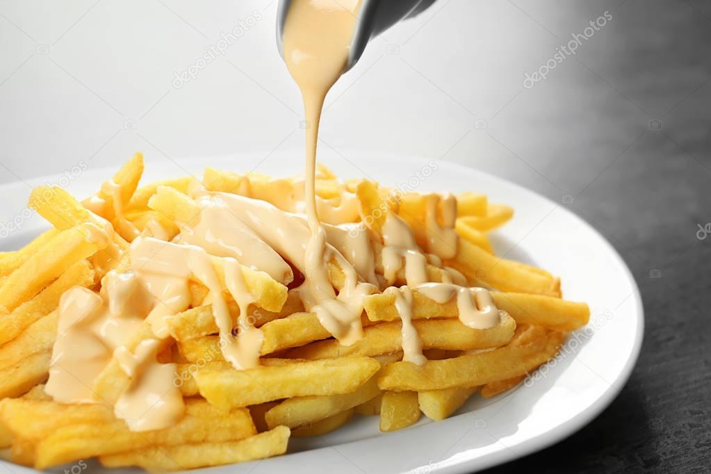 Pouring cheese sauce on french fries