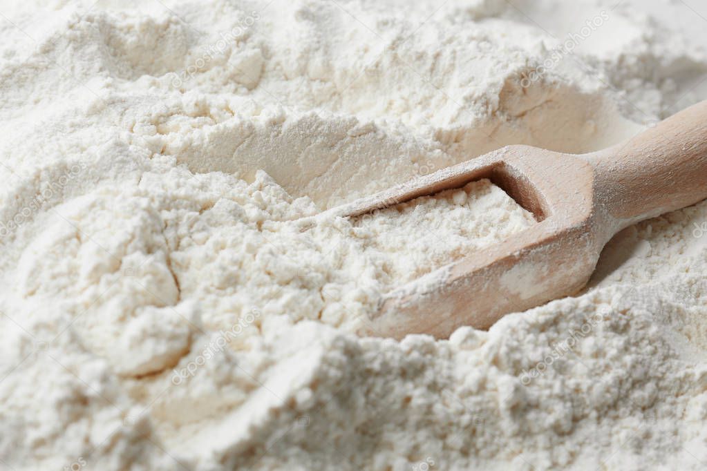 Wooden scoop on flour