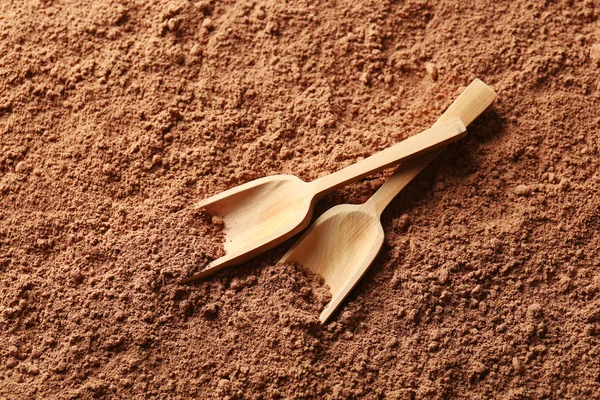 Wooden scoops on cocoa powder background — Stock Photo, Image