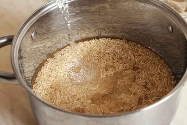 Verter agua en la sartén con arroz integral — Foto de Stock