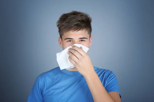 Young man blowing nose in tissue — Stock Photo, Image