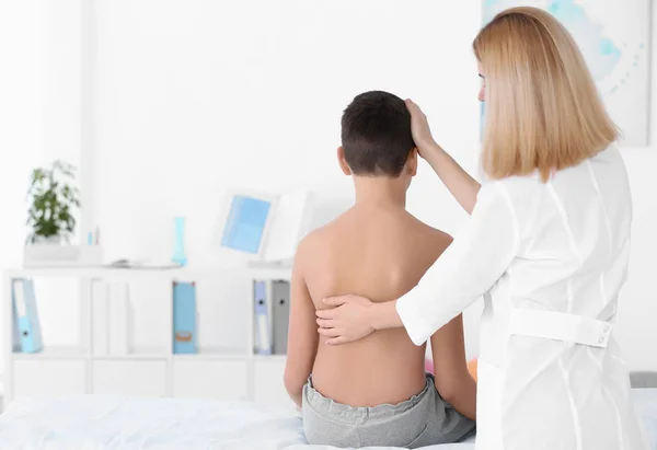 Concept de posture incorrect. Physiothérapeute examinant et corrigeant le dos du garçon — Photo