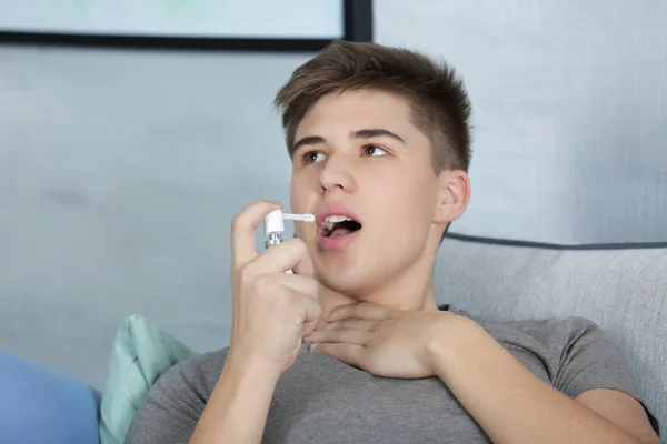 Молодой человек использует спрей для горла — стоковое фото