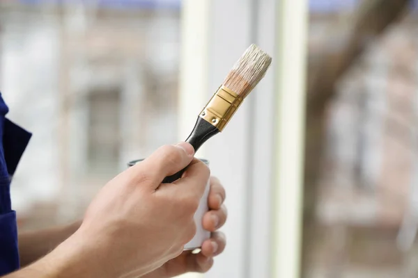 Работник собирается покрасить окно в офисе — стоковое фото