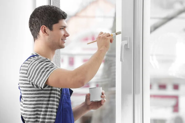 Young worker painting window — Stock Photo, Image