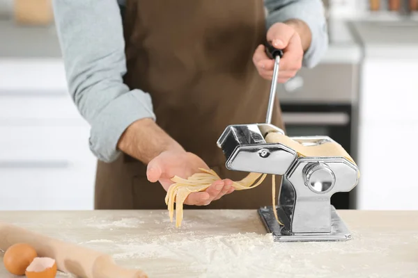 Чоловік готує макарони з машиною на кухні — стокове фото