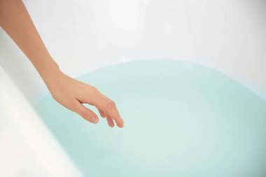 Female hand determining temperature of water clipart