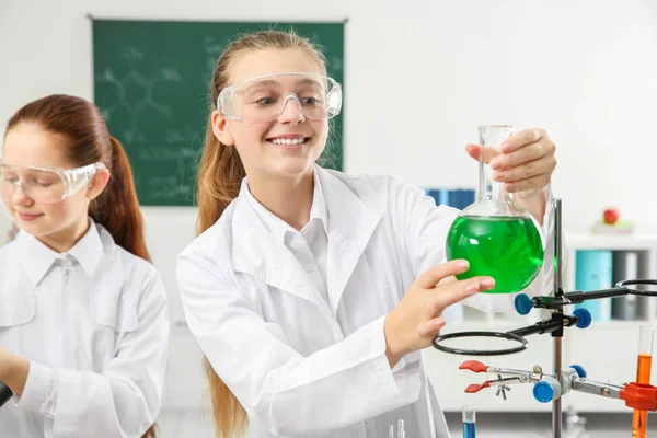 Beautiful scared school girl with flask in chemistry class — Stock Photo, Image